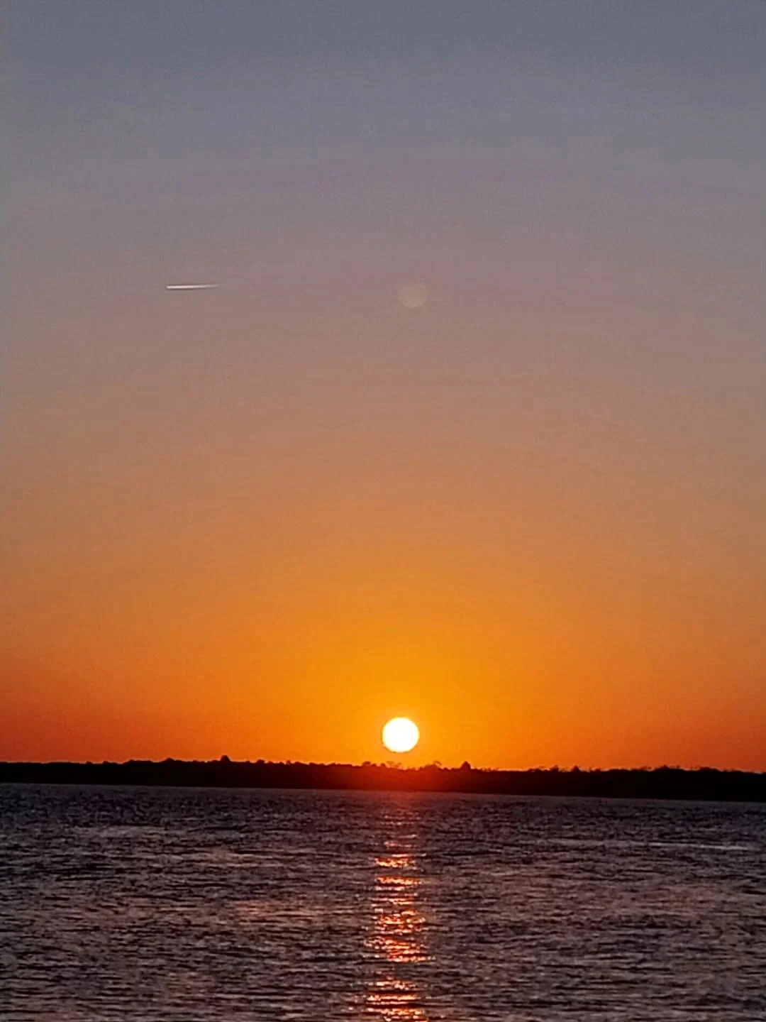 Pôr do sol alaranjado refletindo sobre as águas de Cacha-Pregos